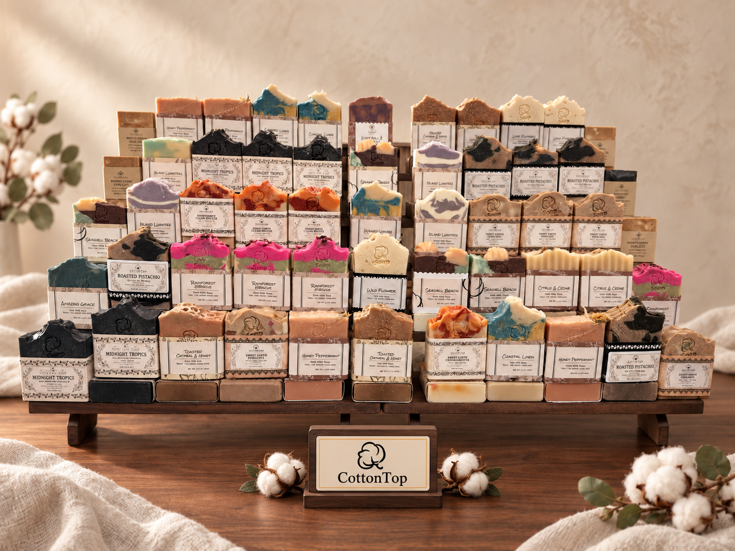 A colorful assortment of CottonTop limited-run artisan soaps displayed on walnut with labeled bars resting in front